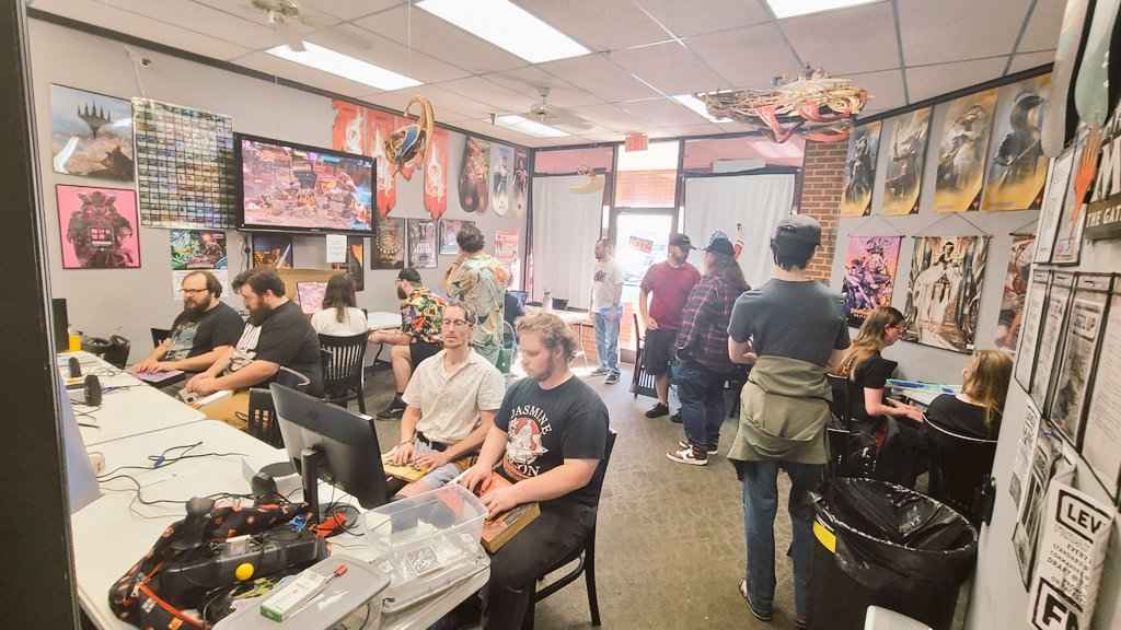 Image of a Saturday meetup for Knoxville, TN's Fighting Game Community. Roughly 15 players pictured in a card shop playing various fighting games.